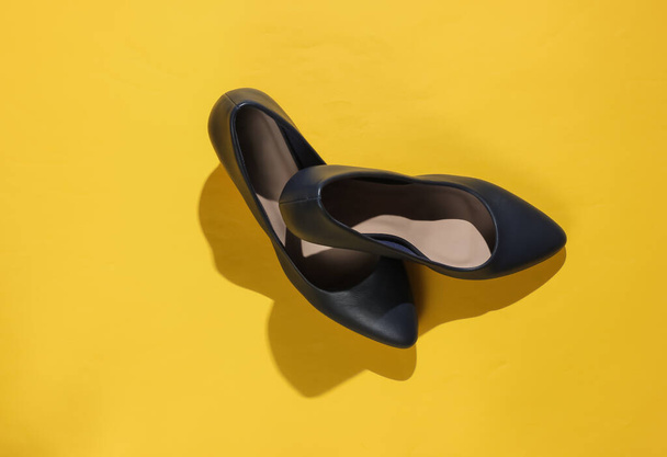 Класичні жіночі туфлі на високому каблуці на жовтому папері. Стильне взуття. Студійний знімок. Мінімалістична мода натюрморт
. - Фото, зображення