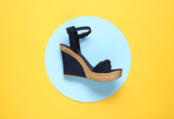 Stylish women's sandal with platform  on yellow background with blue circle in the middle. Stylish shoes. Minimalistic fashion still life. Top view - Fotoğraf, Görsel