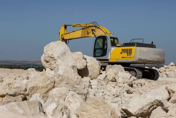 Uma grande escavadora amarela está minando rocha em uma pedreira. - Foto, Imagem