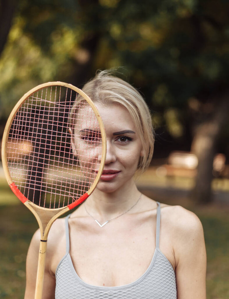 Retrato de mujer atractiva del deporte con raqueta de bádminton en el parque en un día soleado brillante - Foto, Imagen