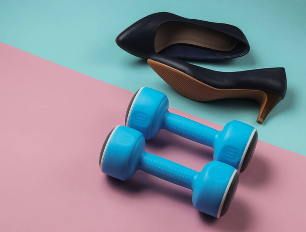 Leddy's sport. Women's high heel shoes with dumbbells on pastel background. Fitness and fashion concept - Photo, Image