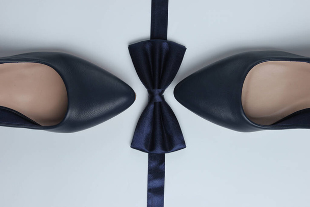Moda minimalista ainda vida. Sapatos de salto alto feminino e gravata borboleta no fundo branco. Vista superior - Foto, Imagem