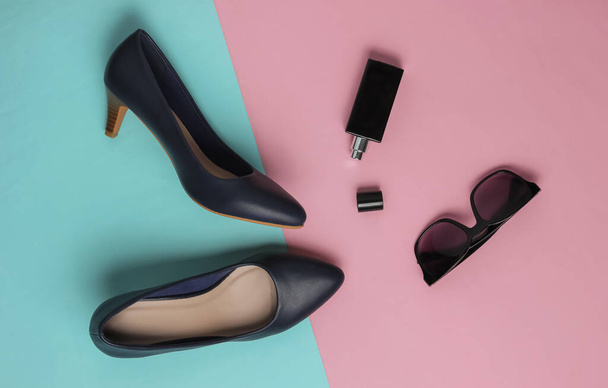 Stylish women's accessories and shoes on pink blue pastel background. Leather high heel shoes, bottle perfume, sunglasses. Top view, Flat lay - Foto, immagini
