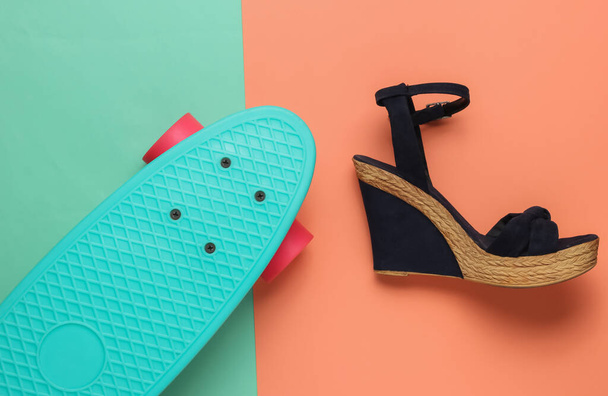 Diversión de verano. Sandalias de mujer en plataforma con cruiser board sobre fondo rosa estudio azul. Disparo de moda, vista superior - Foto, imagen