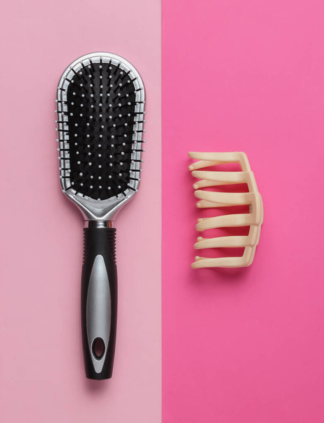 Minimalistic beauty and fashion concept. Women's hair care accessories. Comb, hair clip on pink background. Top view - Photo, Image