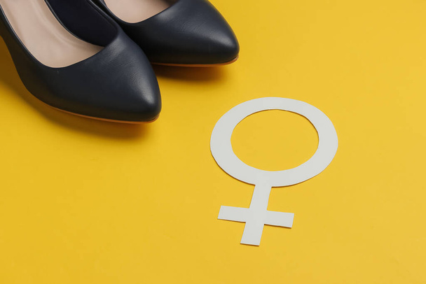 Féminisme. Femme symbole de genre, chaussures à talons hauts sur fond jaune. - Photo, image