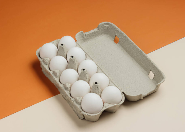 Vassoio di cartone con uova su sfondo beige marrone. Minimalismo concetto di cottura. - Foto, immagini
