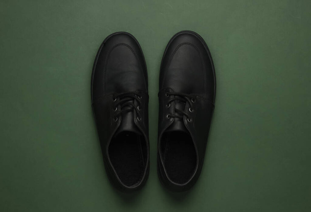 Zapatos negros de cuero para hombre sobre fondo de papel verde. Vista superior - Foto, Imagen