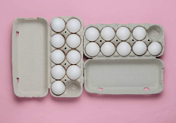 ピンクのパステルの背景に卵と段ボールトレイ。ミニマリズム料理の概念。トップ表示. - 写真・画像