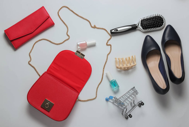 Kadın çantasında ne var? Kadın aksesuarlarıyla kırmızı deri çanta, kozmetik ürünleri, beyaz arka planda yüksek topuklu ayakkabılar. Minimalist moda konsepti. Stüdyo çekimi - Fotoğraf, Görsel
