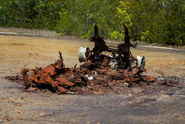 Yanmış bir arabanın paslanmış kalıntıları gelgit tuzu düzlüklerinde terk edilmiş. - Fotoğraf, Görsel