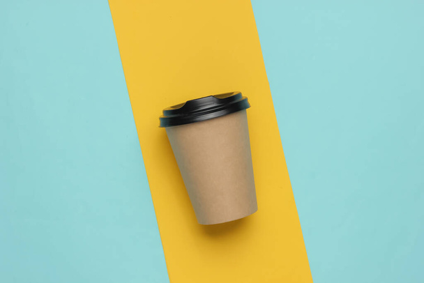 Taza de café de cartón sobre un fondo de papel de color. Vista superior - Foto, Imagen