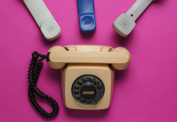 Hotline, concept de bureau. Vieux téléphone rotatif, de nombreux combinés sur fond rose. Vue de dessus. Style rétro - Photo, image