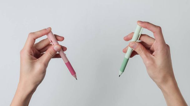 Ambidextr. Naiskädet pitävät kyniä valkoisella pohjalla. Huippunäkymä. Studiokuva - Valokuva, kuva
