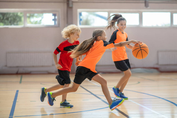 Kids in bright sportswear playing basketball together and feeling competitive - Fotografie, Obrázek
