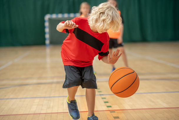 A blonde boy playing with a ball and looking involved - Photo, image