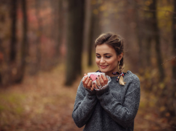 Молодая счастливая женщина пьет чай из чашки в осеннем лесу. Арт-портрет - Фото, изображение