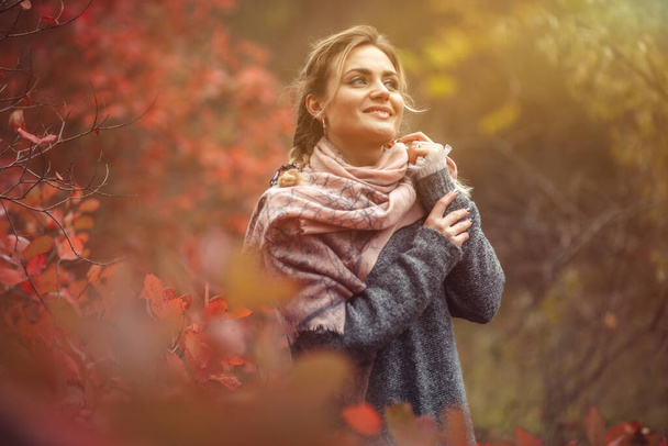Taidemuotokuva. Nuori iloinen nainen syksyllä vaatteet poseeraa metsässä punertava lehdet puita - Valokuva, kuva