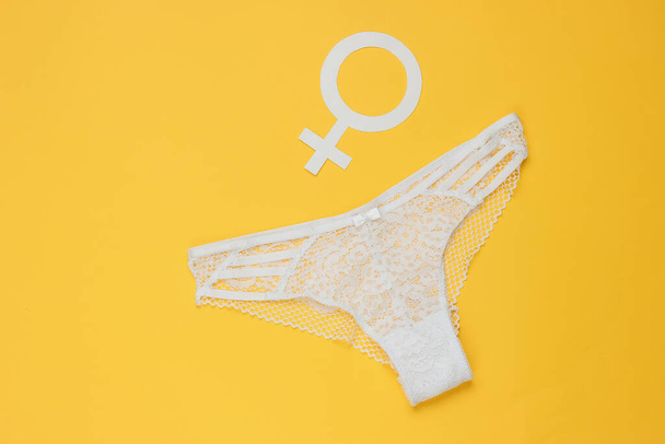 Γυναικεία σέξι δαντελένια εσώρουχα και σύμβολο Femen φύλο σε κίτρινο φόντο. Η έννοια του φεμινισμού. Άνω όψη - Φωτογραφία, εικόνα