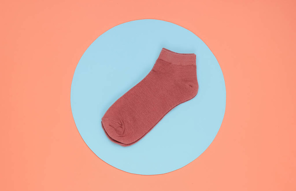 Pink socks on pink background with blue circle in the middle. Minimalistic fashion still life. Top view - Fotografie, Obrázek