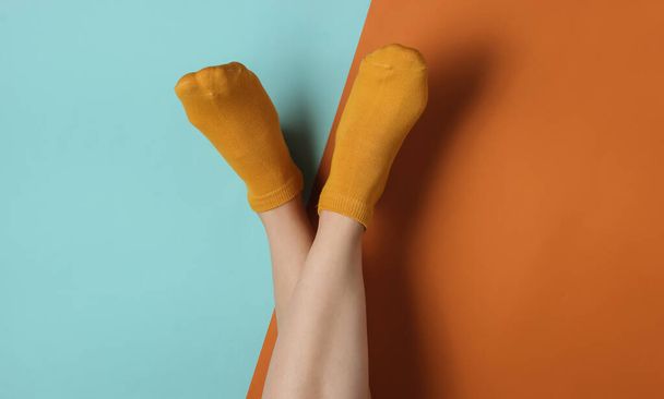 Weibliche schlanke Beine in orangefarbenen Socken auf blaubraunem Hintergrund. Ansicht von oben - Foto, Bild