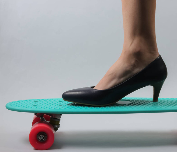 Λεπτά γυναικεία πόδια με κλασσικά ψηλοτάκουνα παπούτσια σε πίνακα καταδρομικών. Στιγμιότυπο σε λευκό φόντο. - Φωτογραφία, εικόνα