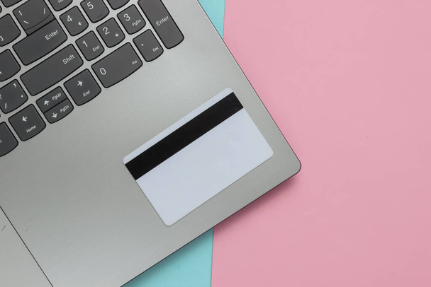 Laptop i karta bankowa na różowym niebieskim tle pastelowym. Zakupy online. Widok góry. Minimalizm - Zdjęcie, obraz