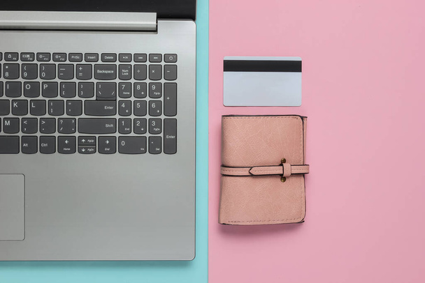 ピンクブルーのパステルカラーの背景にノートパソコン、財布、銀行カード。オンラインショッピング。最上階だ。ミニマリズム - 写真・画像