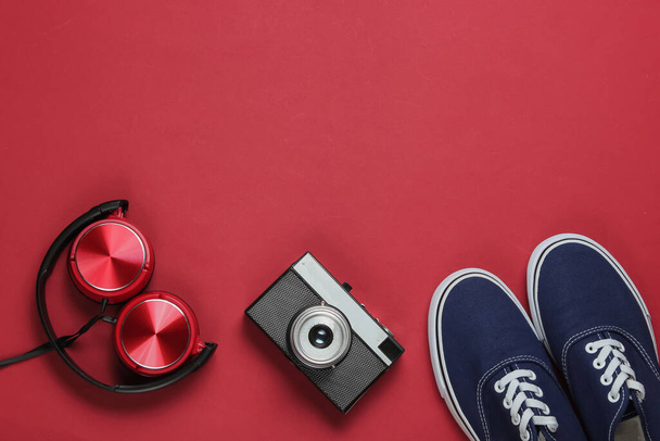 Stylische Kopfhörer, Old-School-Turnschuhe, Filmkamera auf rotem Hintergrund. Retro-Stil. 80er Jahre. Popkultur. Ansicht von oben - Foto, Bild