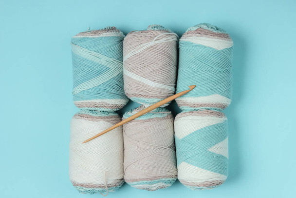 Woolen skeins of thread and crochet hook on blue background. Top view - Foto, immagini