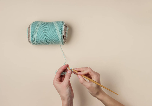 Mãos femininas fio de malha com um crochê de madeira e fios de lã no fundo bege. hobby dona de casa - Foto, Imagem