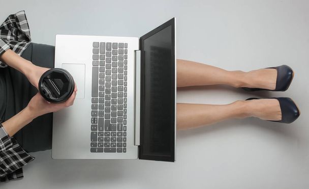 Επιχειρηματίας με επίσημα ρούχα απολαμβάνει φορητό υπολογιστή, ενώ κάθεται σε λευκό φόντο και κρατώντας φλιτζάνι καφέ. Απομακρυσμένη, ηλεκτρονική δουλειά, υπάλληλος γραφείου. Άνω όψη - Φωτογραφία, εικόνα