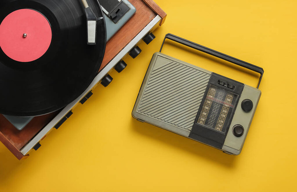 Retro rádió vevő, régimódi bakelitlejátszó sárga háttérrel. Hetvenes évek médiája. Felülnézet - Fotó, kép