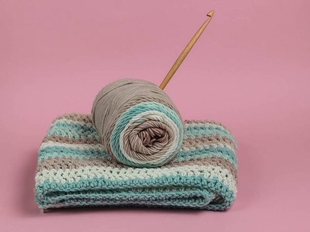Yarn with skeins of woolen threads and wooden crochet for knitting on pink background. - Photo, image