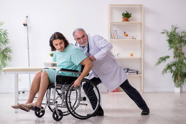 Jeune homme en fauteuil roulant et médecin traumatologue expérimenté - Photo, image