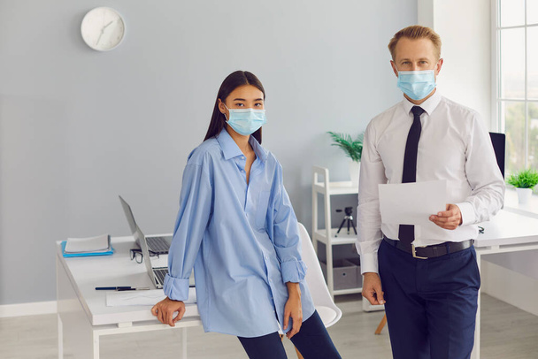 Felelős férfi és nő, üzleti vállalkozás dolgozói, orvosi arcmaszkot viselnek a munkahelyükön - Fotó, kép