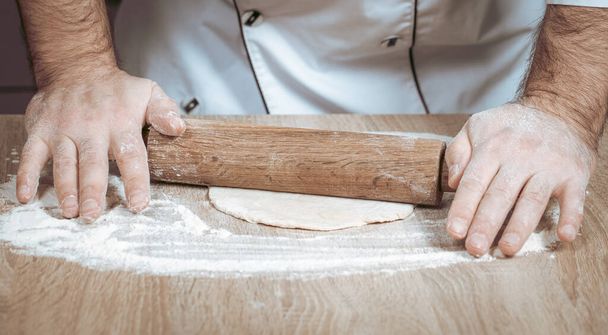 male cook kneads dough on the table, hands close-up - Photo, image