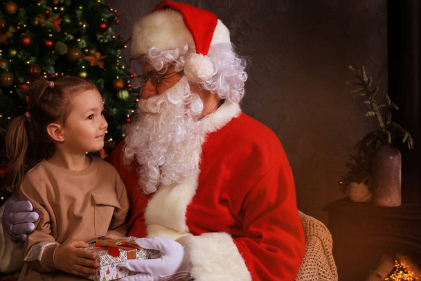 Santa Claus and child at home. Christmas gift. Family holiday concept - Фото, изображение