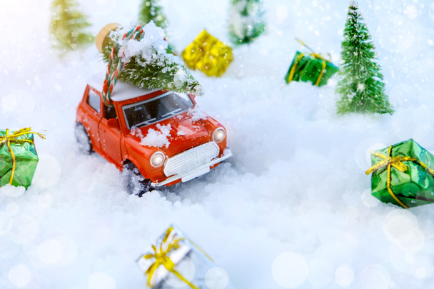 Albero di Natale su auto giocattolo rosso con sfondo albero sfocato e neve. Biglietto di festa di Natale e nuovo anno 2021 concetto di sfondo, copia lo spazio. - Foto, immagini