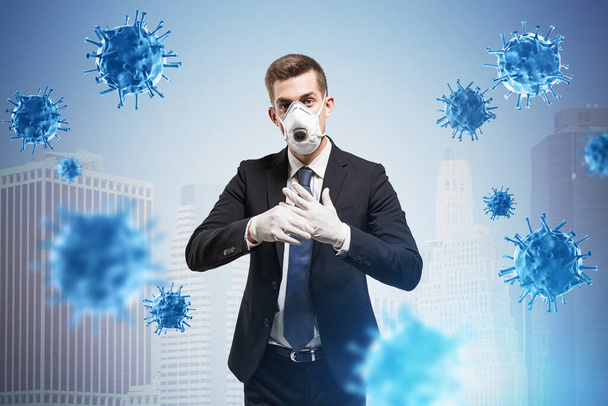 Young European businessman standing in protective mask and rubber gloves in blurry city with double exposure of coronavirus. Toned image - Photo, Image