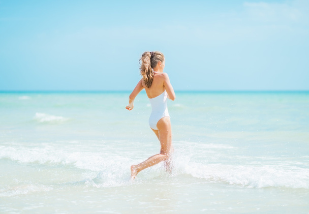 Young woman in swimsuit running into sea - Φωτογραφία, εικόνα