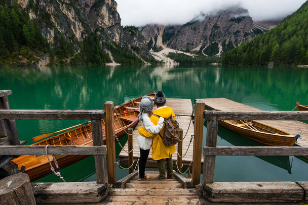 Beautiful couple of young adults visiting an alpine lake at Braies, Italy - Tourists with hiking outfit having fun on vacation during autumn foliage - Concepts about travel, lifestyle and wanderlust - Φωτογραφία, εικόνα
