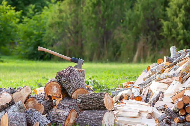 Gehacktes Brennholz und Holzbeil auf der grünen Wiese. Brennholz für die Wintersaison ernten. - Foto, Bild