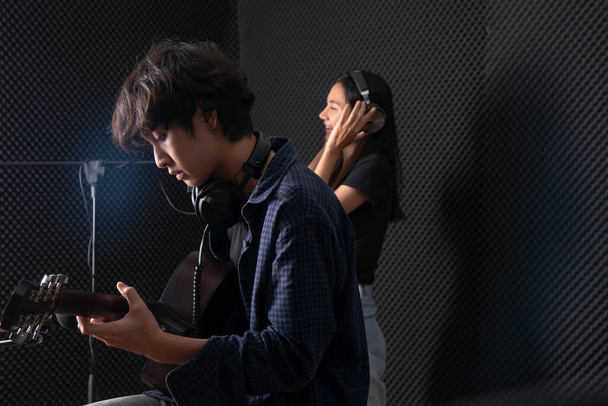 Junger Mann spielt mit Freund im Plattenraum des Musikstudios Gitarre - Foto, Bild