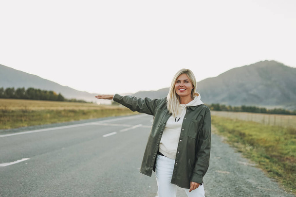 Красива усміхнена блондинка молода жінка мандрівник у білому светрі на дорозі, поїздка в гори, потяг
 - Фото, зображення