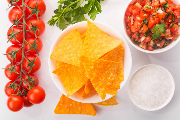 Mexicaanse tomaat salsa met tortilla chips op een witte achtergrond. Flat Lay, Bovenaanzicht. - Foto, afbeelding