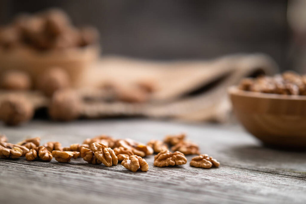 Fresh walnut kernels and whole walnuts in a bowl on rustic old wooden table. Healthy organic food, BIO viands, natural background. Copy space for your advertising text message. - 写真・画像
