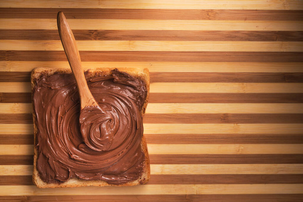 Closeup of toast with cream chocolate and spoon. Sweet food. - Fotoğraf, Görsel