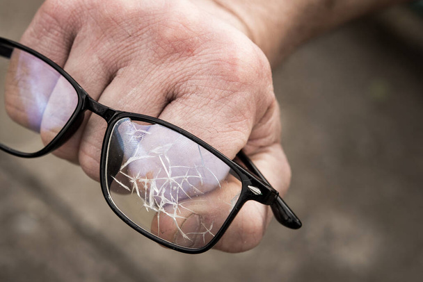 το χέρι ενός άντρα σφιγμένο σε μια γροθιά με σπασμένα γυαλιά. έννοια της αποτυχίας, θυμός και επιθετικότητα. - Φωτογραφία, εικόνα