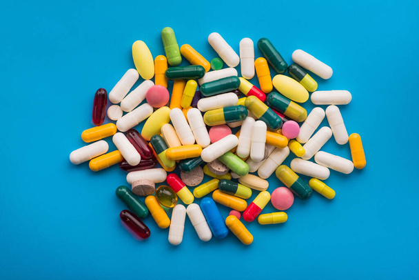 Many colored pills and capsules on a blue background - Photo, image